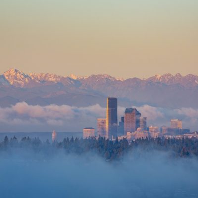 North America, United States, Washington. Seattle skyline and Olympic mountains viewed from Bellevue at sunrise on a foggy morning.