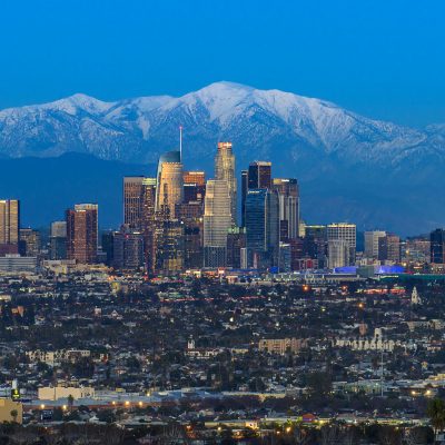 Aerial view of the downtown Los Angeles skyline at dusk with the snow capped San Gabriel mountains as a background